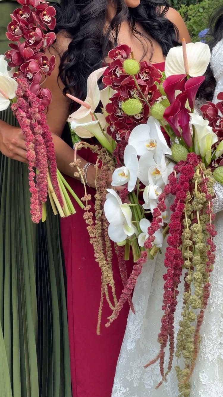 10 Wedding Themes Winter Couples Will Love in 2026 2 Floral bouquets with white orchids and deep red flowers held by women in colorful dresses.