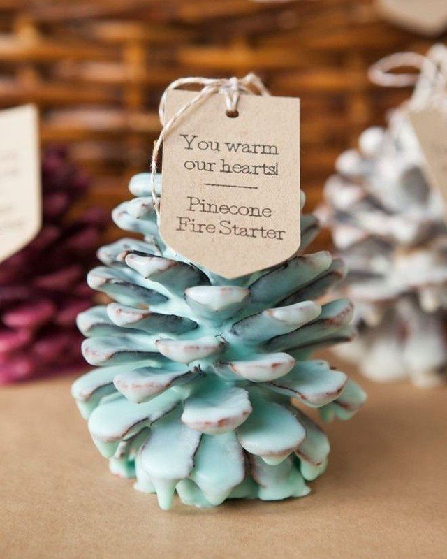 10 Wedding Themes Winter Couples Will Love in 2026 7 A light blue pinecone-shaped candle with a decorative paper tag attached by twine.