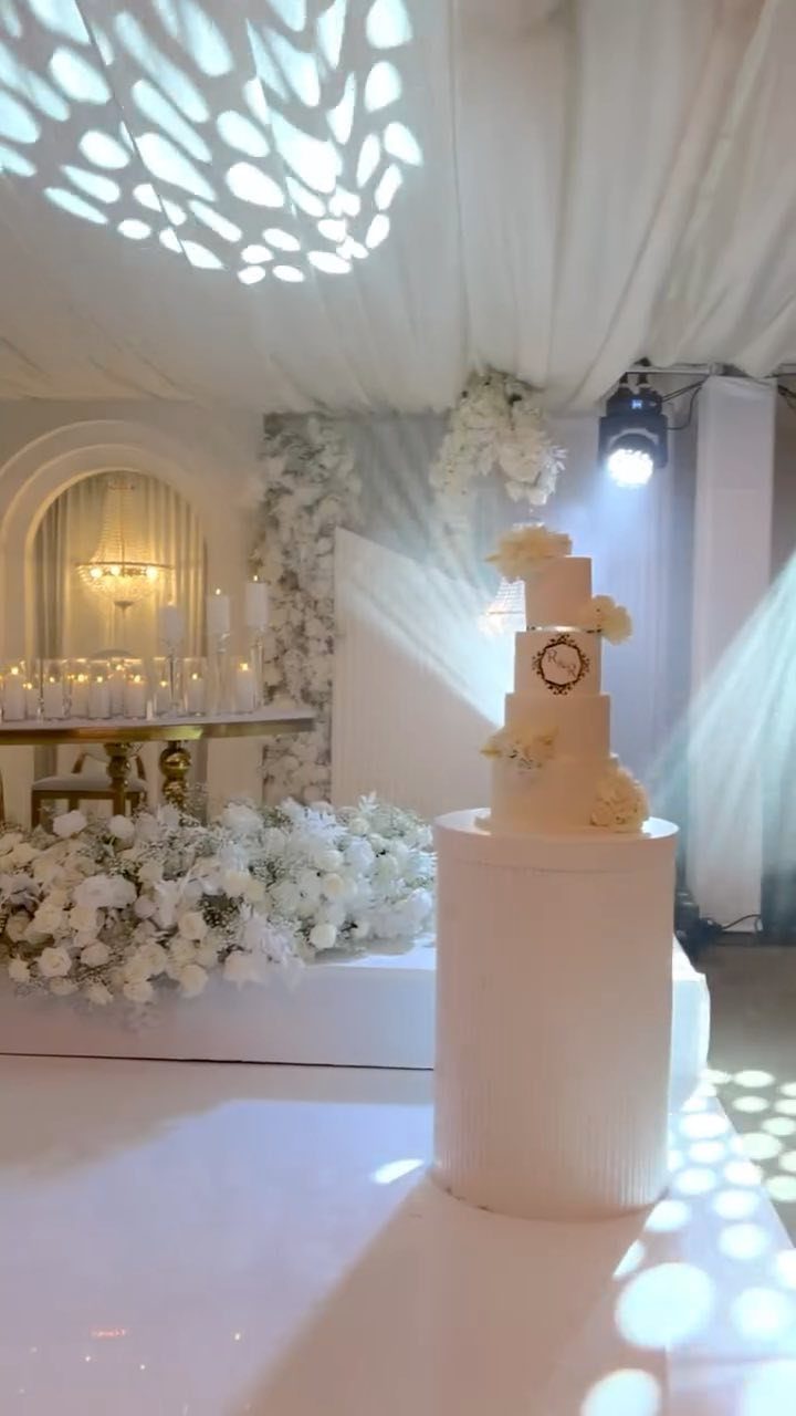 10 Wedding Themes Winter Couples Will Love in 2026 9 A white wedding cake on a pedestal with dappled light patterns projected on the floor and ceiling.