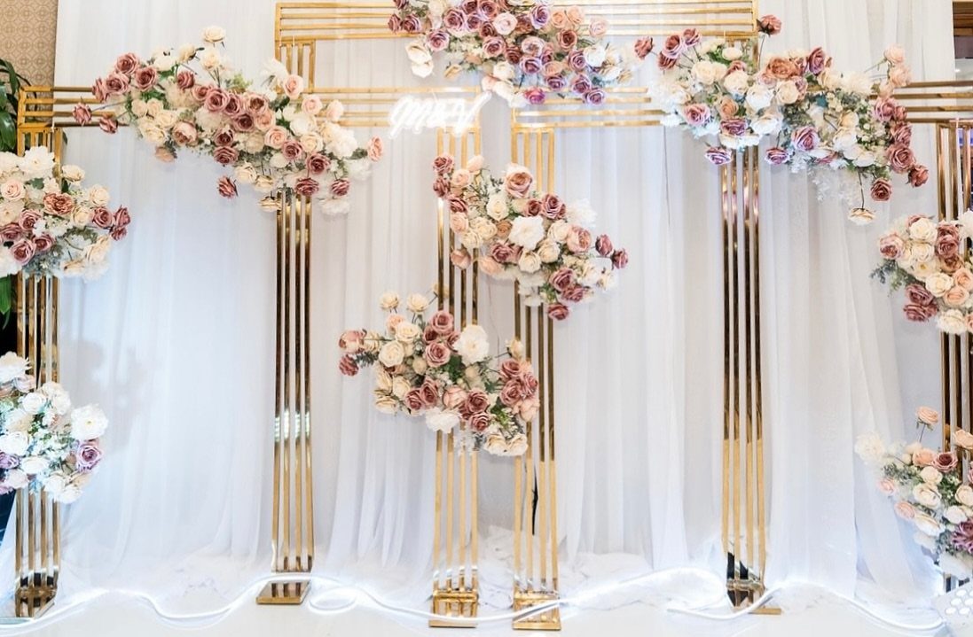 7 Wedding Tree Decorations That Work Outside the Ballroom 5 Gold metal frames decorated with pink and cream faux flowers against white draped fabric.