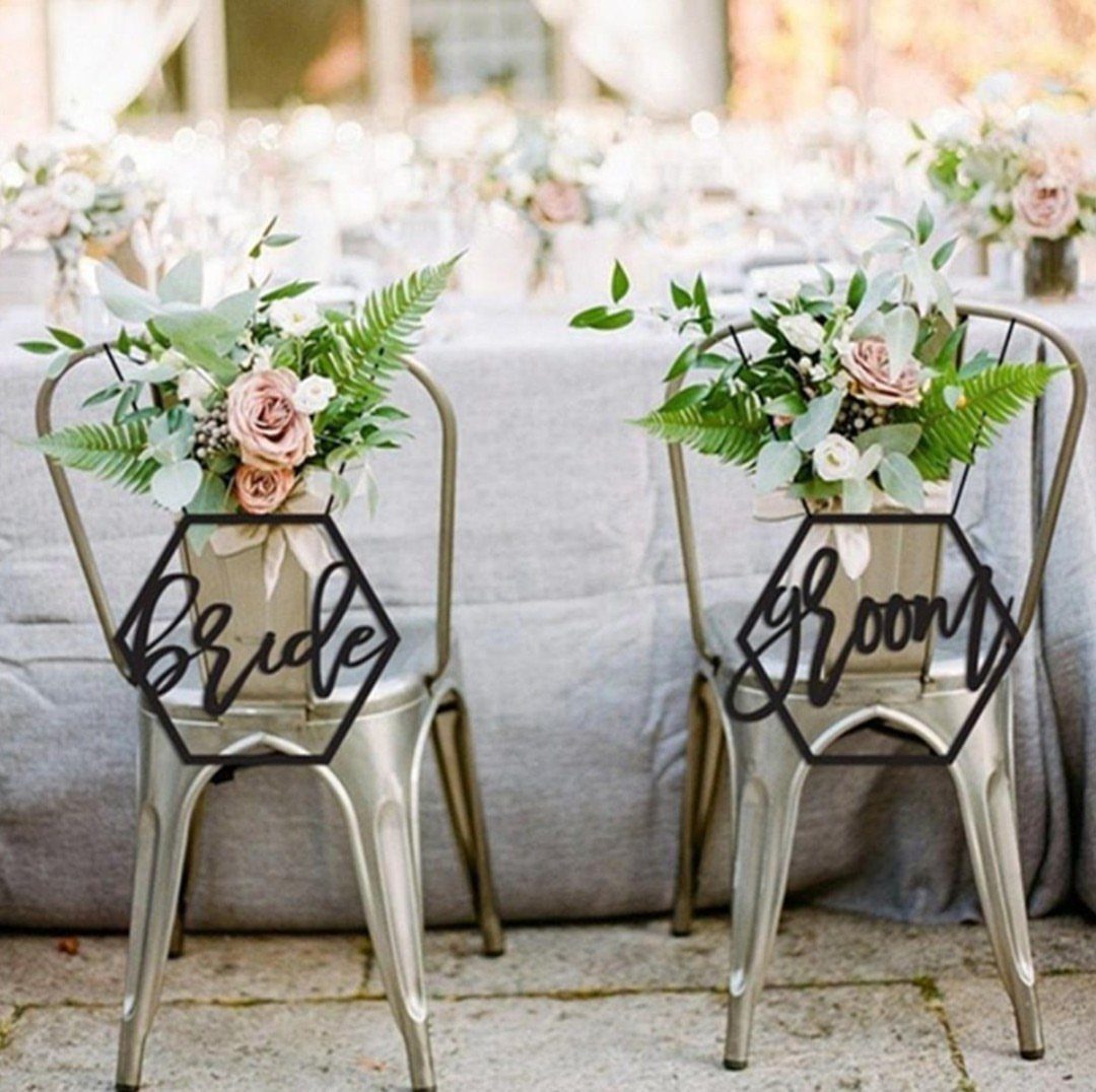 7 Wedding Tree Decorations That Work Outside the Ballroom 4 Two metal chairs featuring floral arrangements and black hexagonal signs reading Bride and Groom.