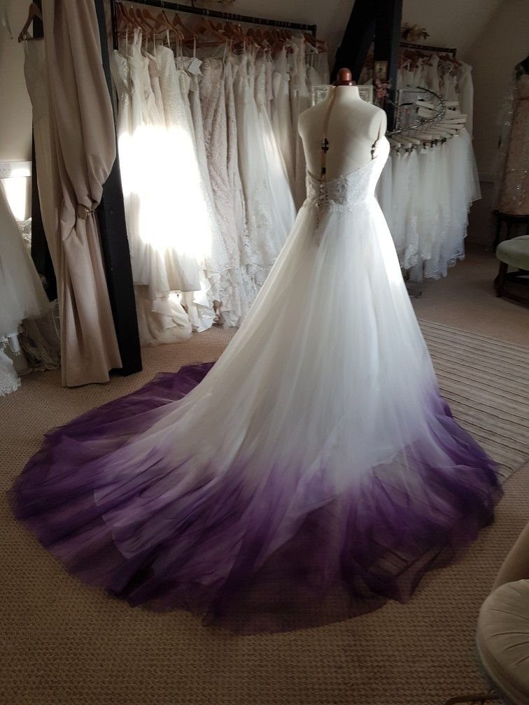 A white wedding dress with a purple dip-dyed tulle skirt displayed on a mannequin.