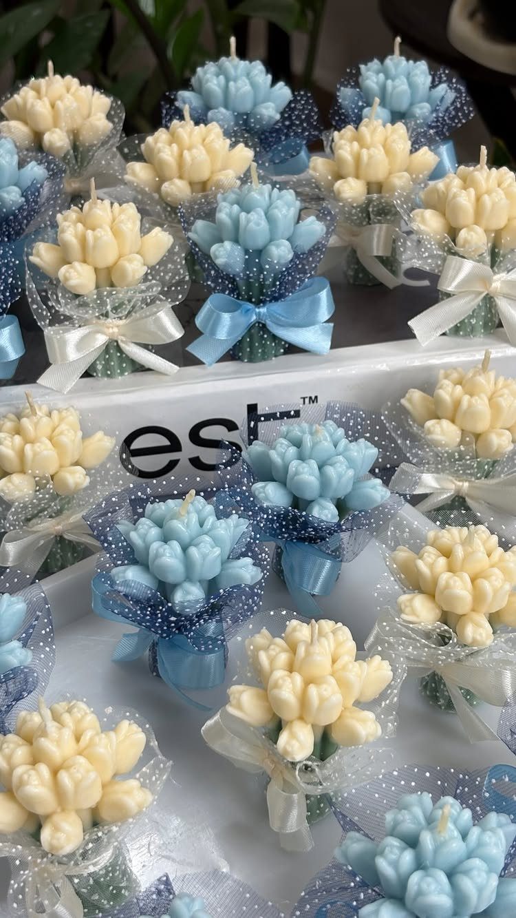 Small flower-shaped candles wrapped in sparkling tulle and tied with satin ribbons on a tray.