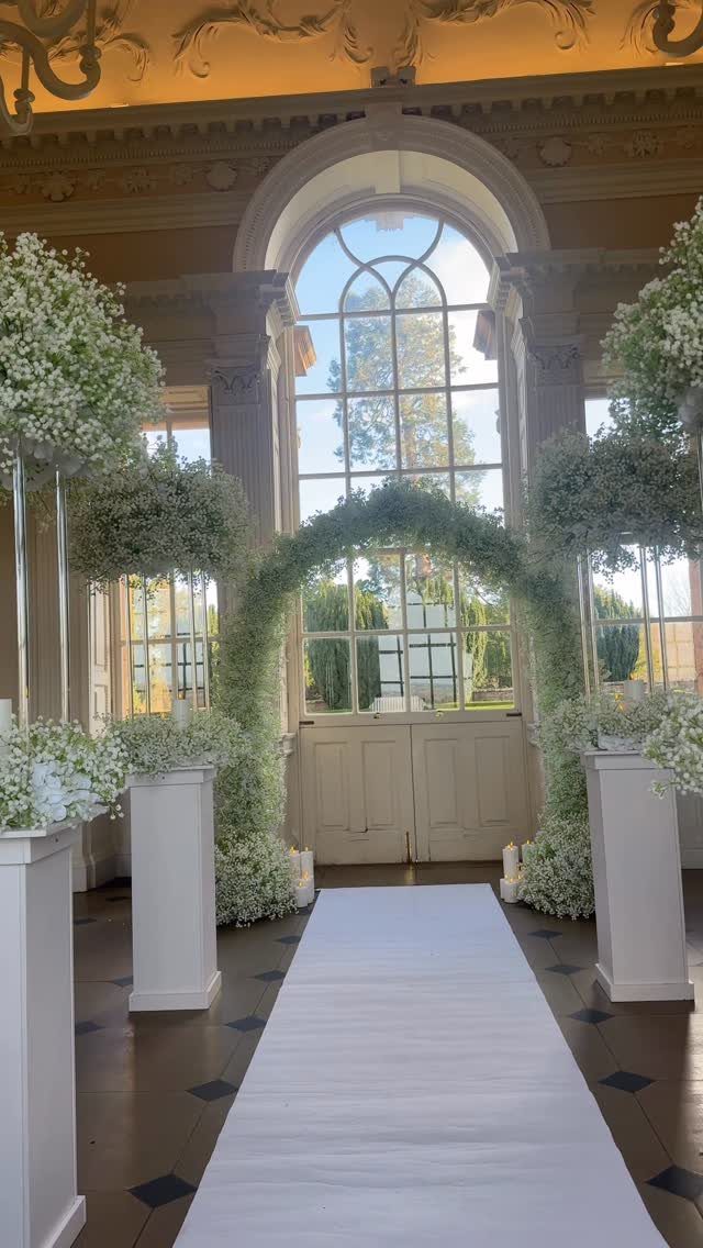 19 Winter Wonderland Wedding Ideas for a Modern Celebration 5 A white wedding aisle runner lined with tall pedestals and an archway covered in baby's breath.