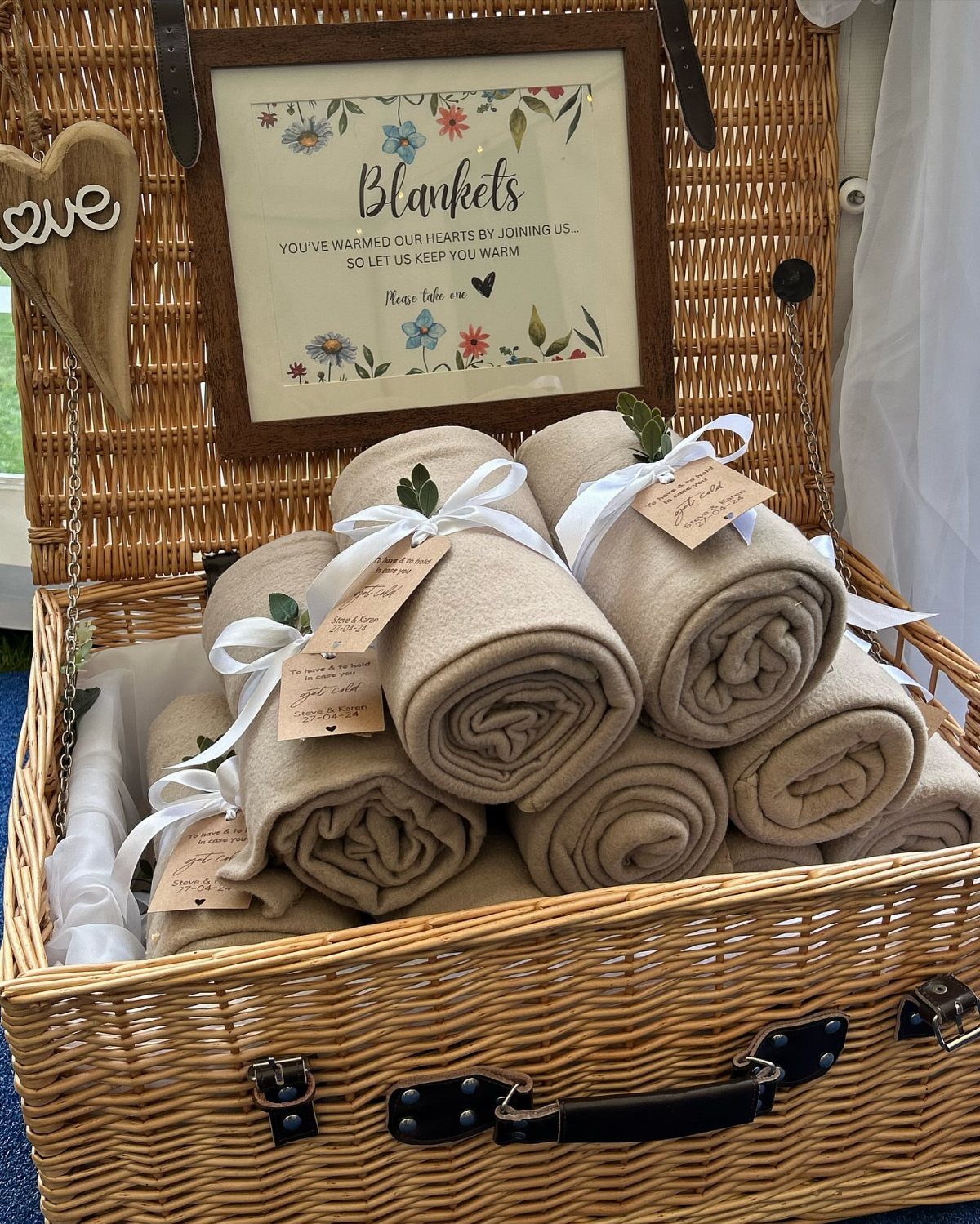 19 Winter Wonderland Wedding Ideas for a Modern Celebration 7 Rolled beige blankets with white ribbons and tags inside a large wicker basket.