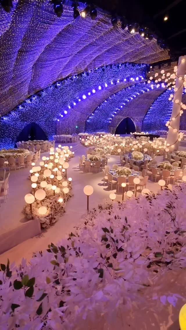 19 Winter Wonderland Wedding Ideas for a Modern Celebration 6 A grand wedding reception hall featuring massive arches of blue and white fairy lights across the ceiling.