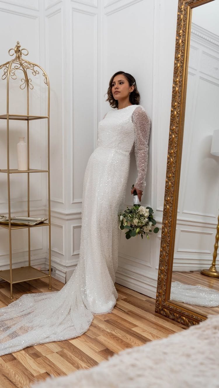 19 Winter Wonderland Wedding Ideas for a Modern Celebration 9 A woman wearing a long-sleeved sequined wedding dress holding a white flower bouquet.