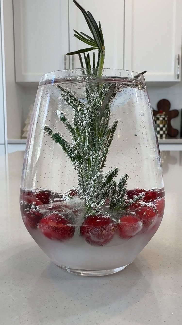 19 Winter Wonderland Wedding Ideas for a Modern Celebration 8 A clear glass containing red cranberries and rosemary sprigs dusted with white powder.