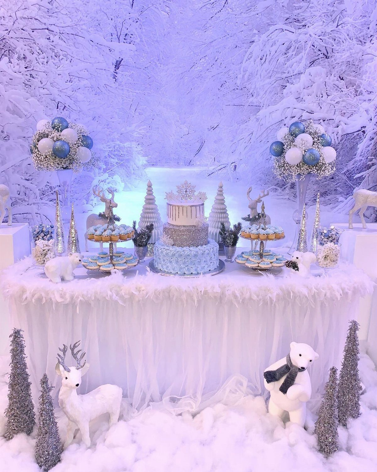 19 Winter Wonderland Wedding Ideas for a Modern Celebration 16 A winter themed dessert table with a blue cake and snowy forest decorations.